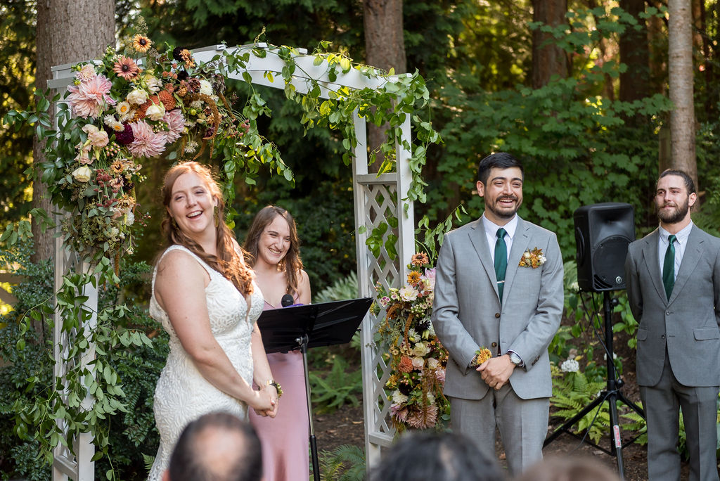 Bride and groom saying their vows in front of a floral arch