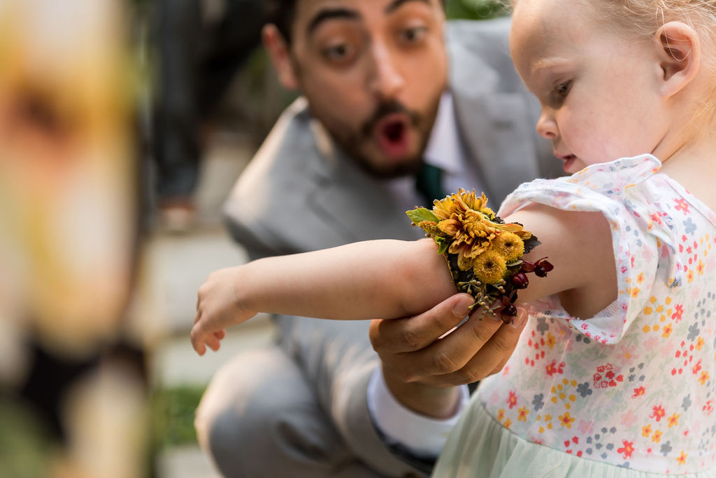 The groom putting floral jewelry on a baby