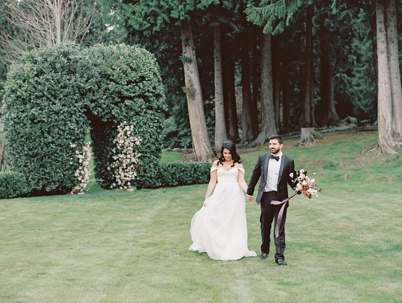 A bride and groom walking across the lawn of Chateau Lill holding hands