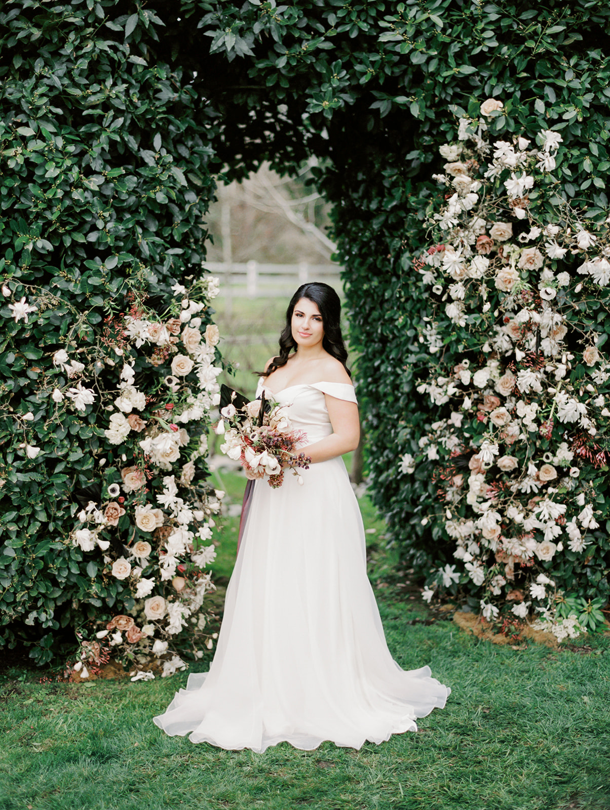 the bride standing in front of a floral arch installation in Chateau Lill, holding a bouquet