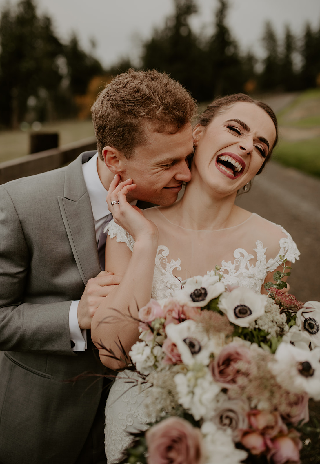 Couple laughing and embracing while holding bouquet