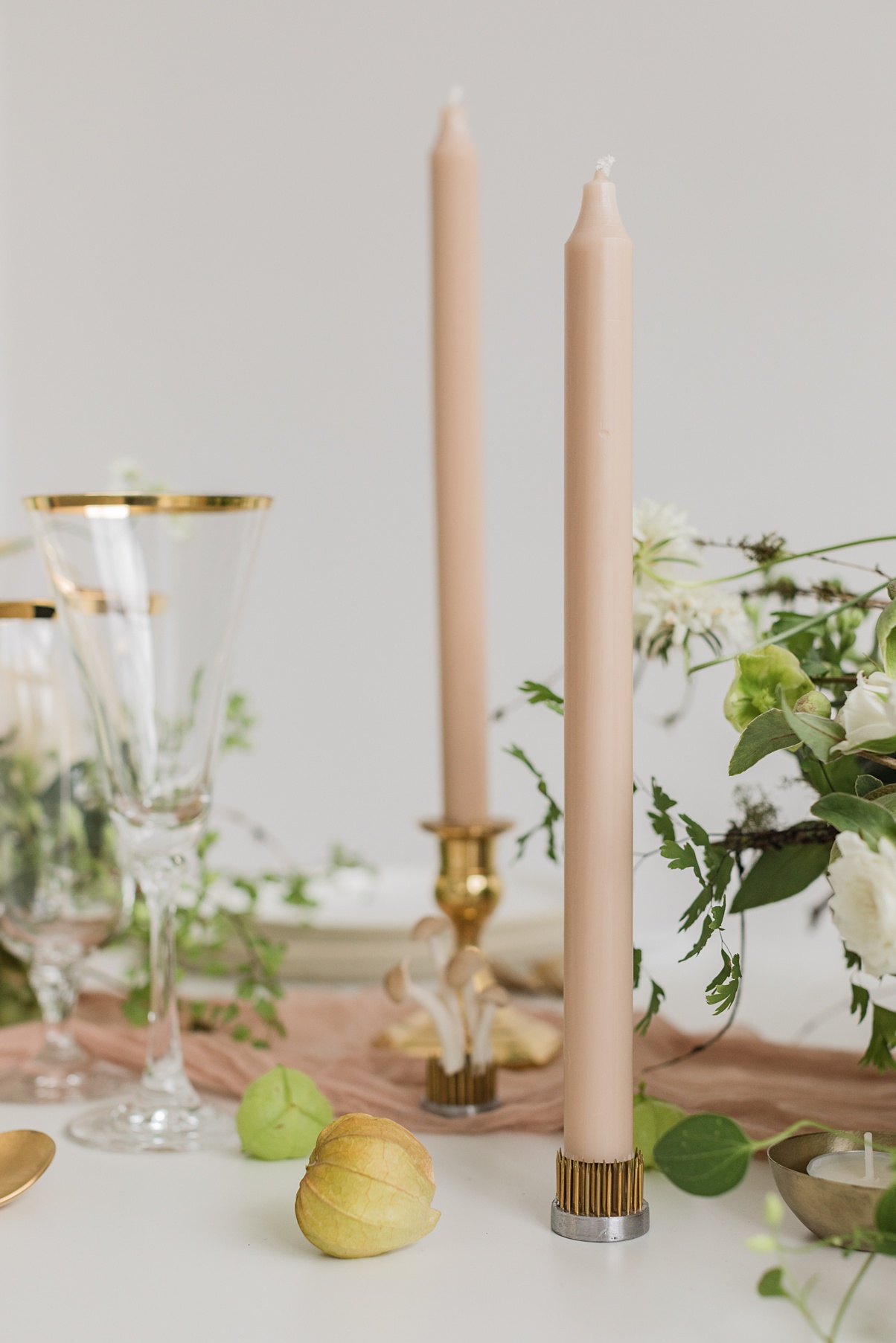A white table with tan taper candles and mushrooms