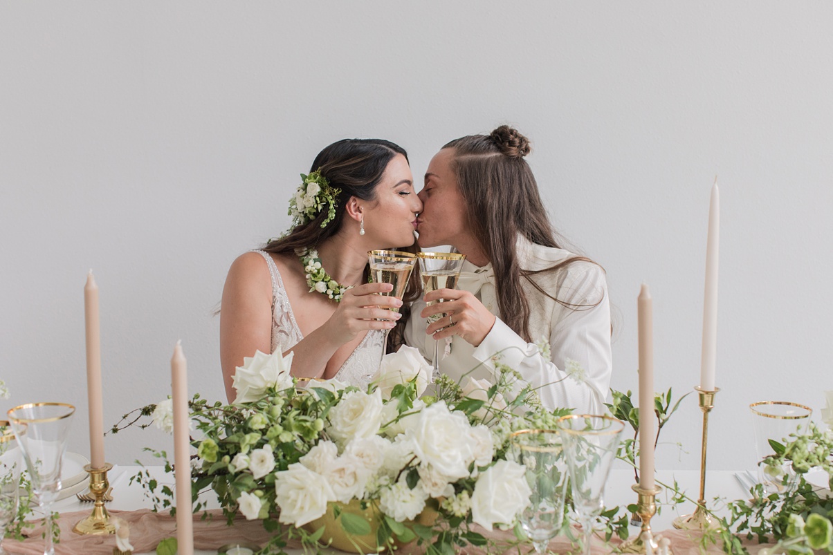 Brides kissing while toasting their champagne glasses