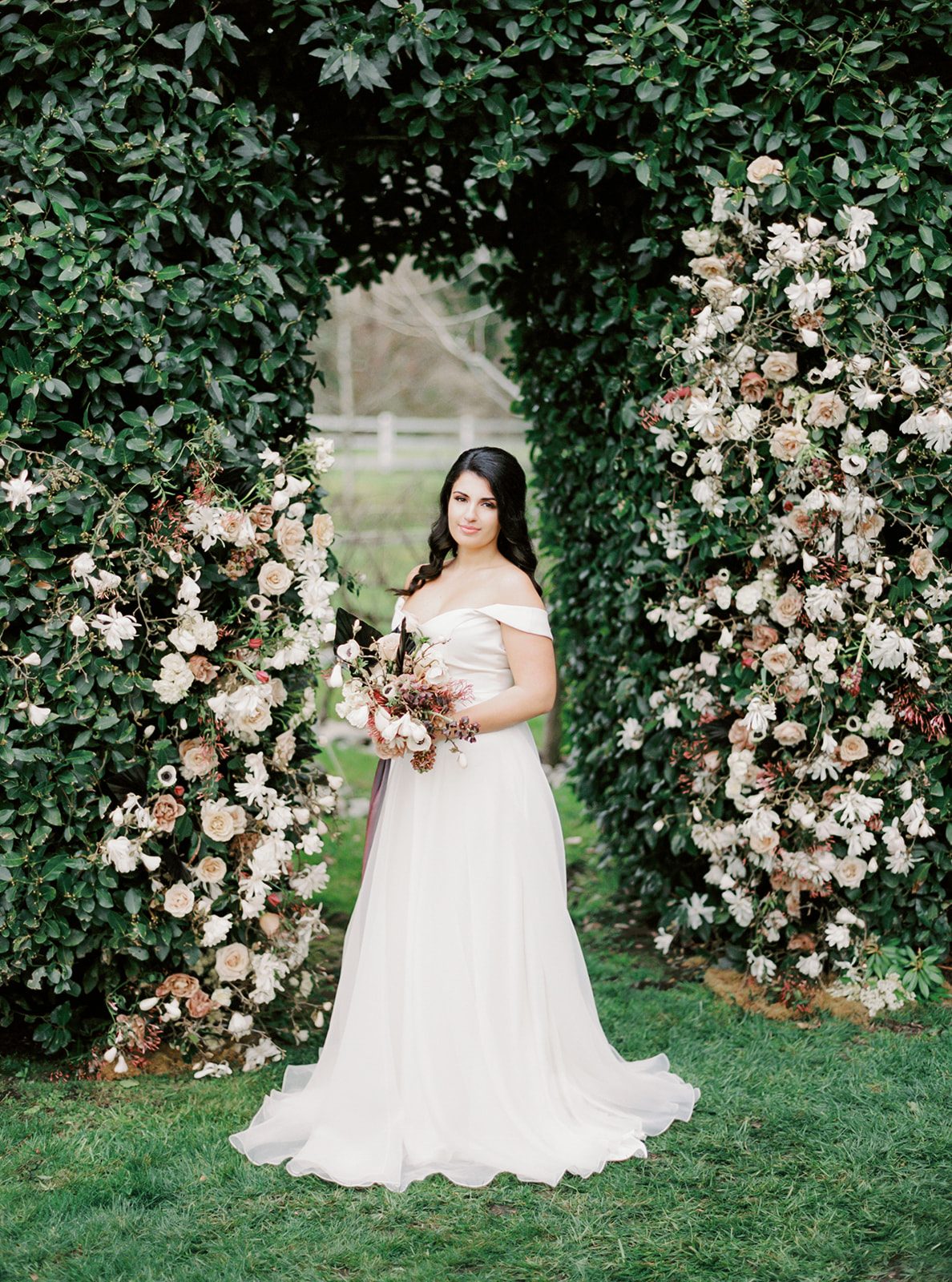 a bride standing in front of a floral hedge installation at Chateau Lill