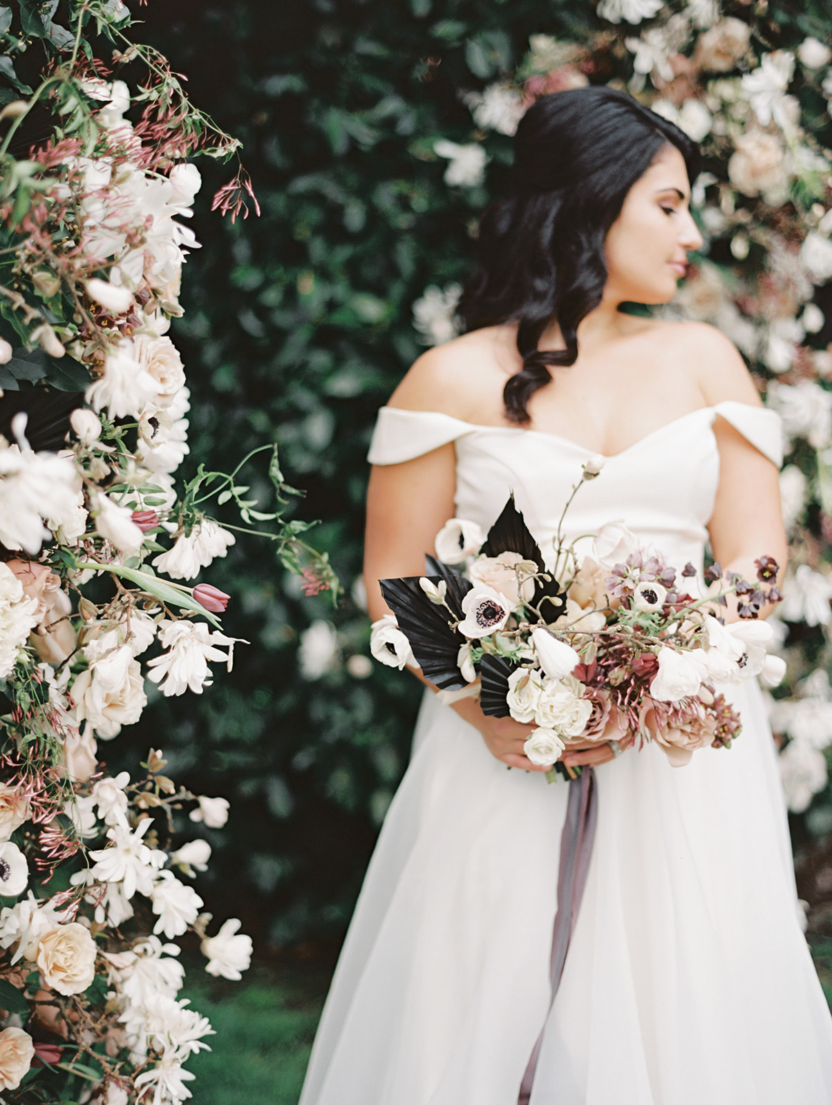 A bride holding a wedding bouquet with anenomes, roses, and tulips