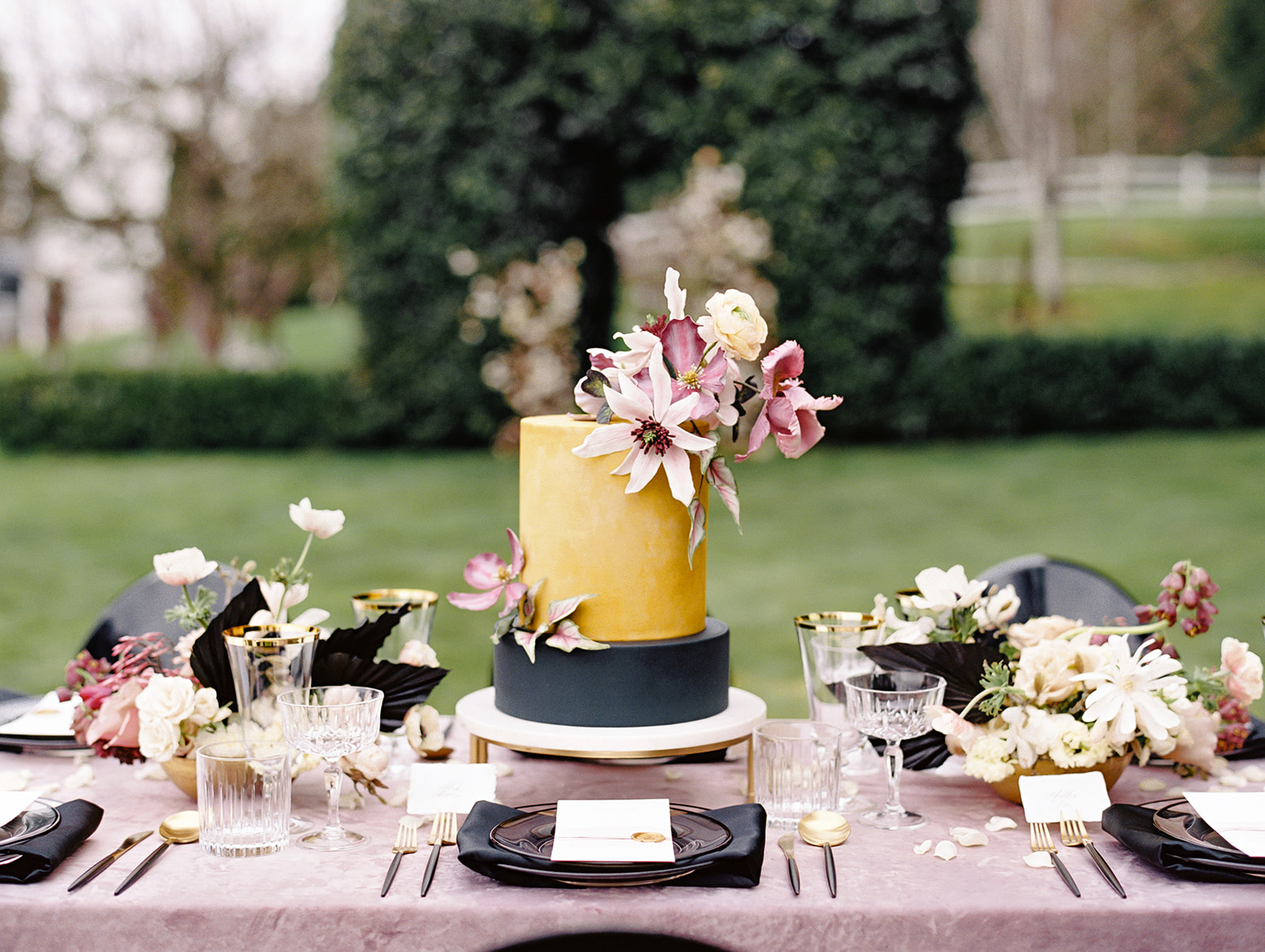 a table set with velvet linen, a cake with sugar flowers, and floral centerpieces