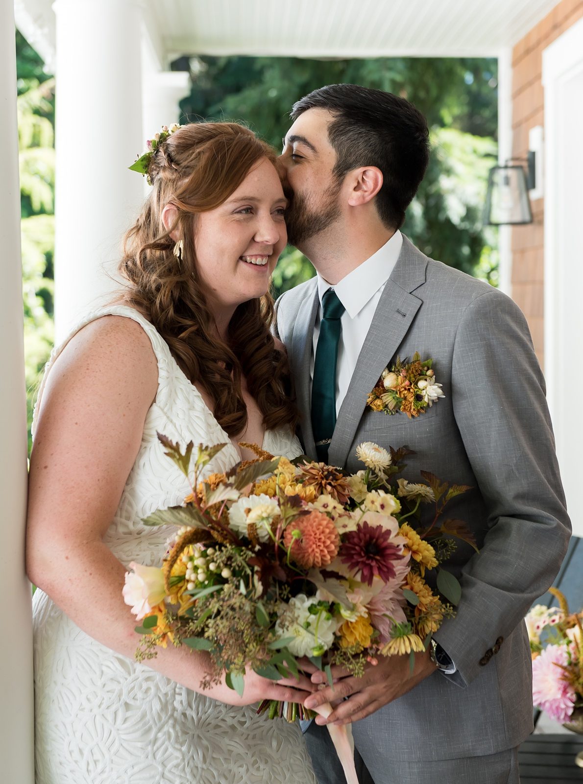 A bride and groom hold a summer bouquet