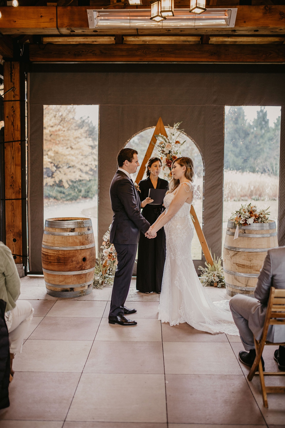 the couple holding hands in front of their ceremony florals in the tented gazebo