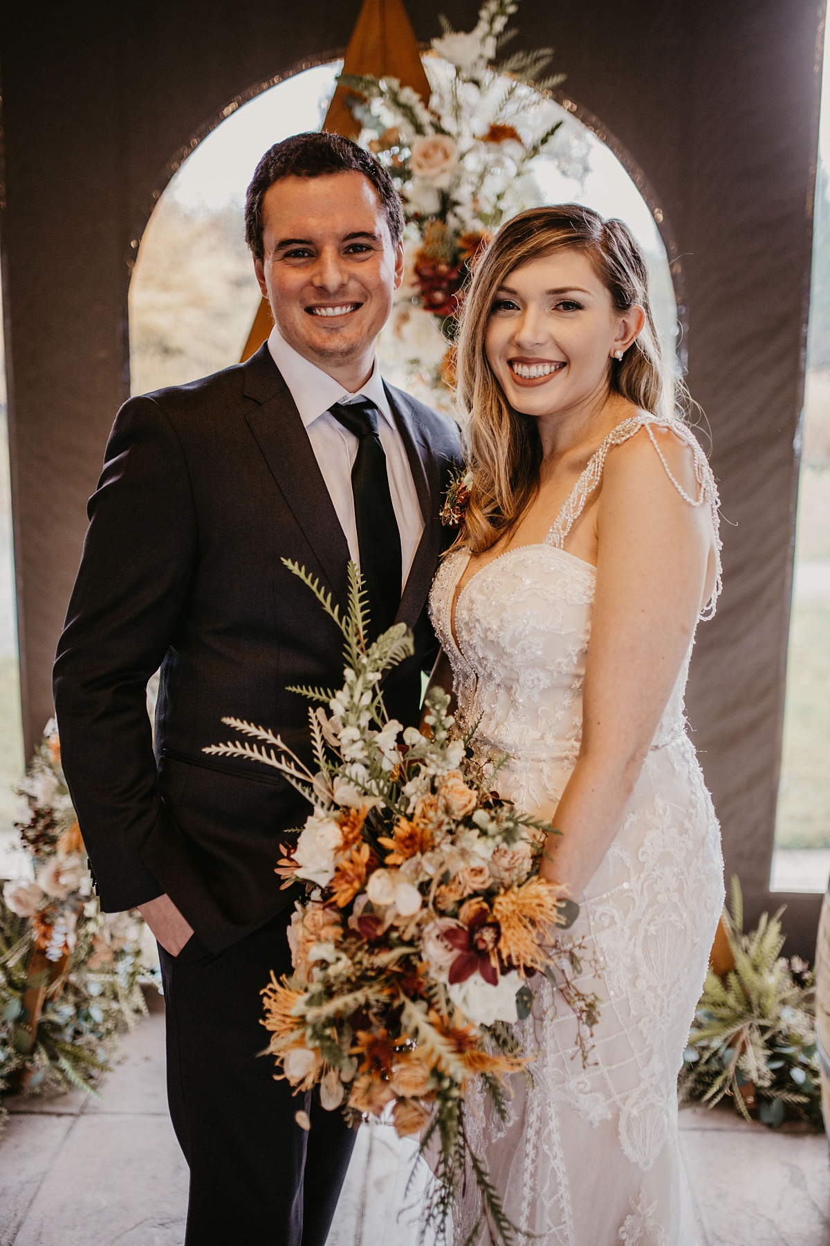 a bride and groom smiling as the bride holds her bridal bouquet