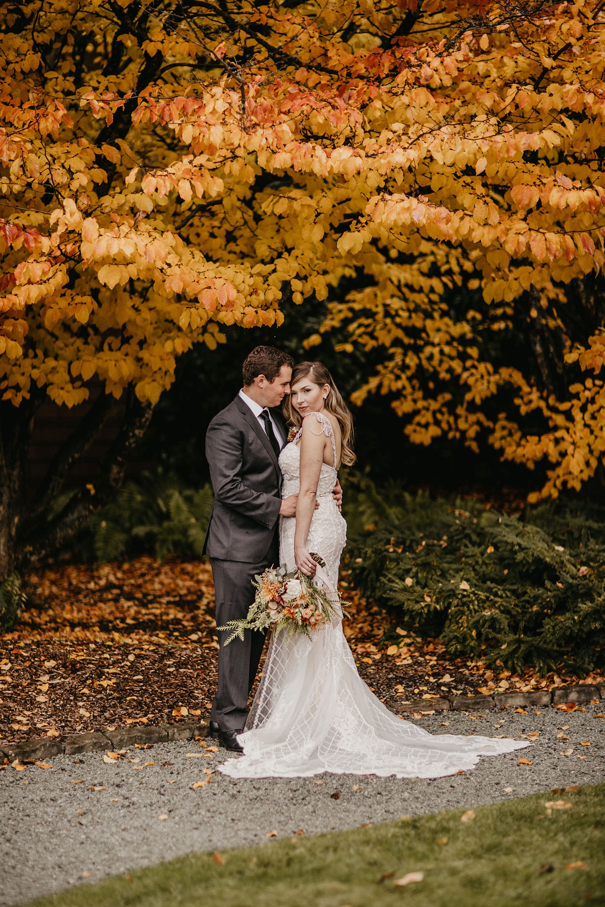 a bride and groom stand under fall foliage at the Willows Lodge