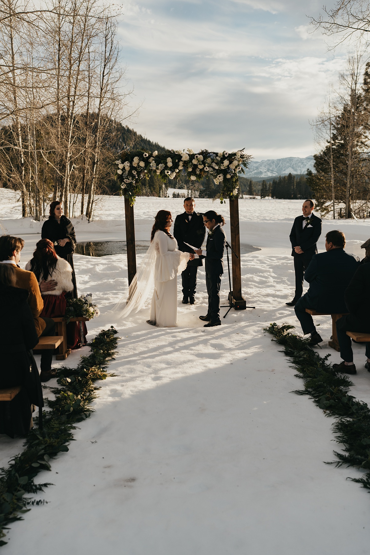 The couple standing at their wedding ceremony with mountains in the background