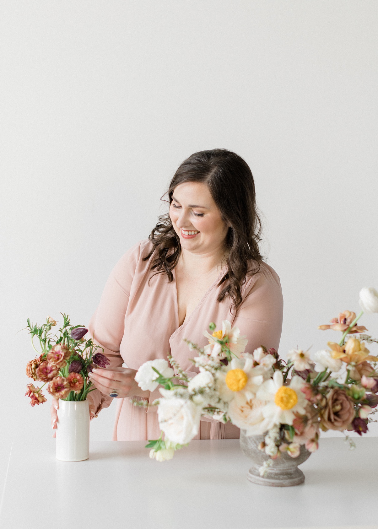 Seattle wedding florist and owner of Bloom Poet, Carolyn Kulb, stands at a table arranging flowers
