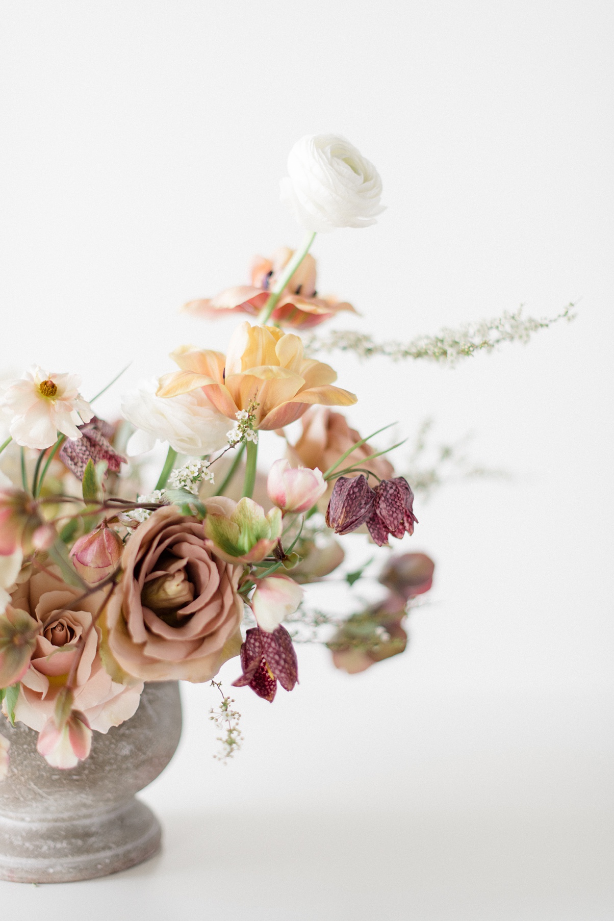 A floral compote wedding centerpiece with white, taupe, mauve, and blush spring flowers