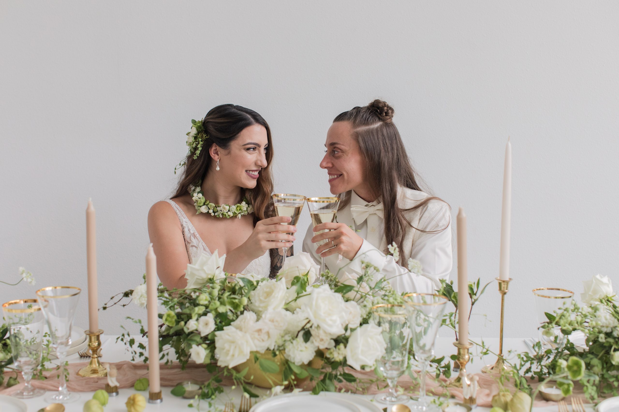 A modern white wedding with two brides toasting champagne