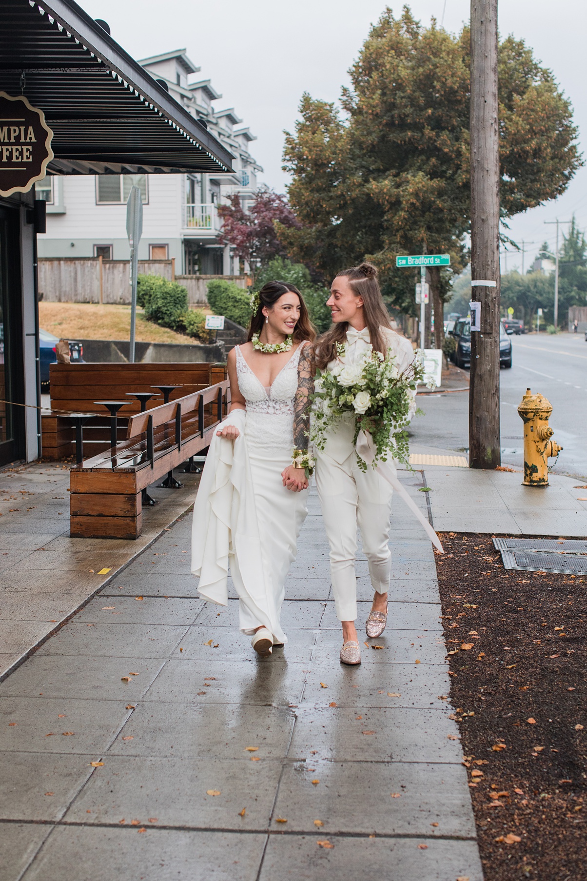 A queer couple walks outdoors in Seattle holding hands after wedding
