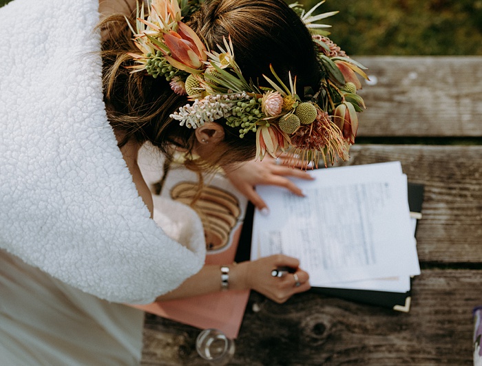 The bride signs the marriage certificate and shows off her tropical flower crown