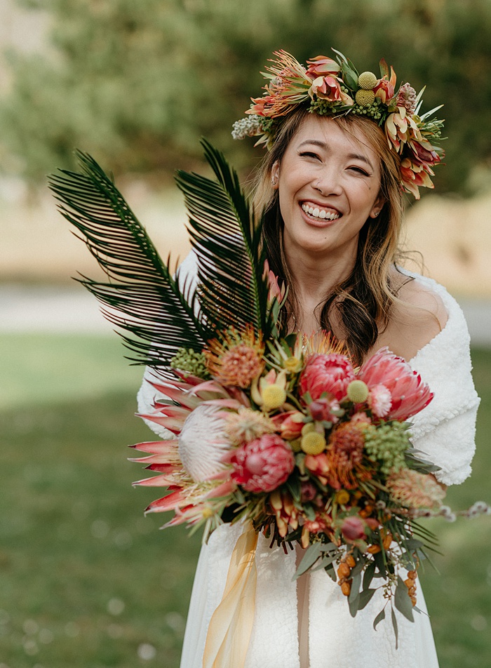 The bride holding her tropical wedding flower bouquet and smiling