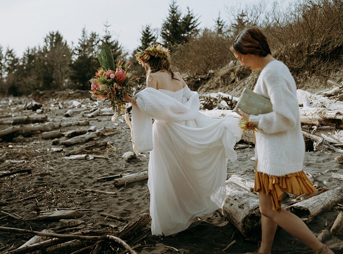 The bride gets an assist holding her dress in the hike to the beach