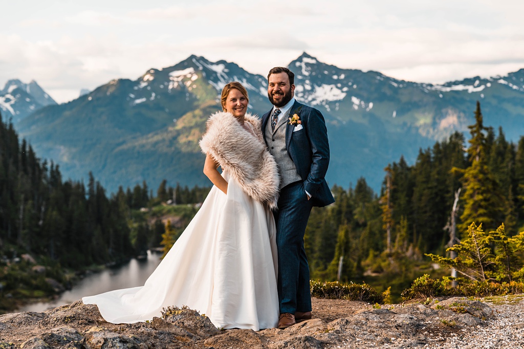 A couple stands on a mountaintop after their wedding