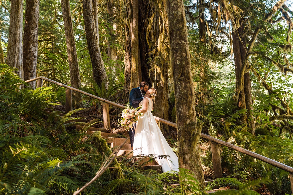 The couple kisses on a woodland trail