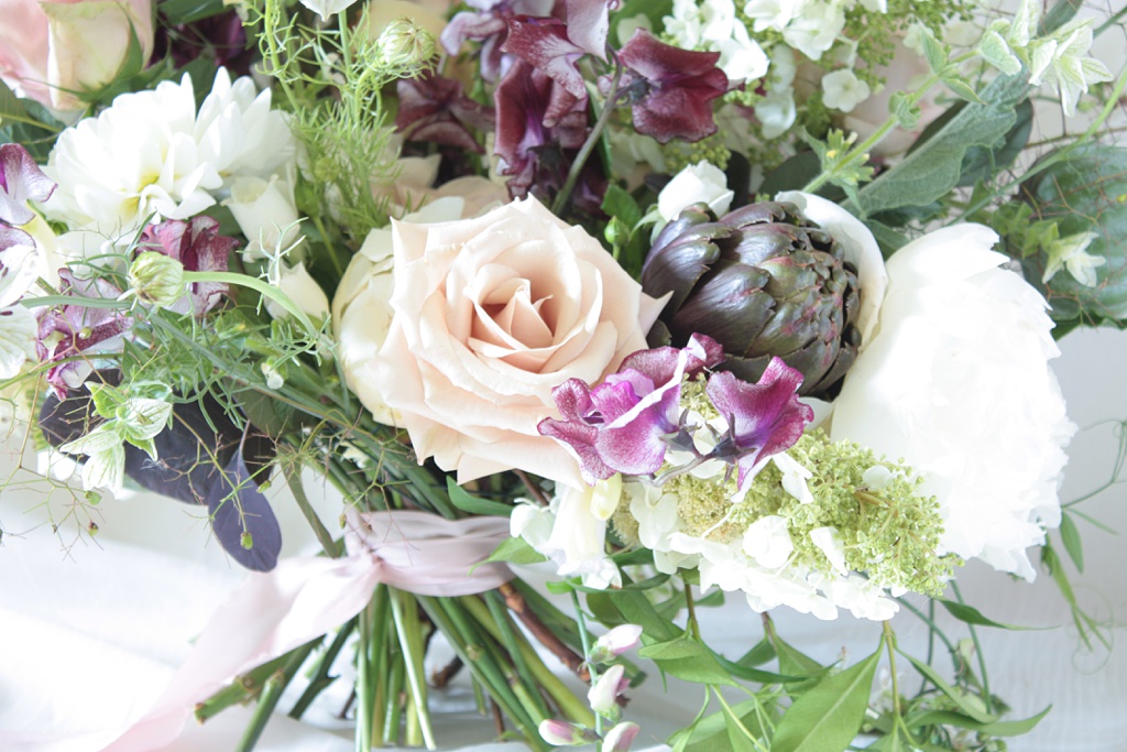 A wedding bouquet with sweet peas, peonies, and artichokes