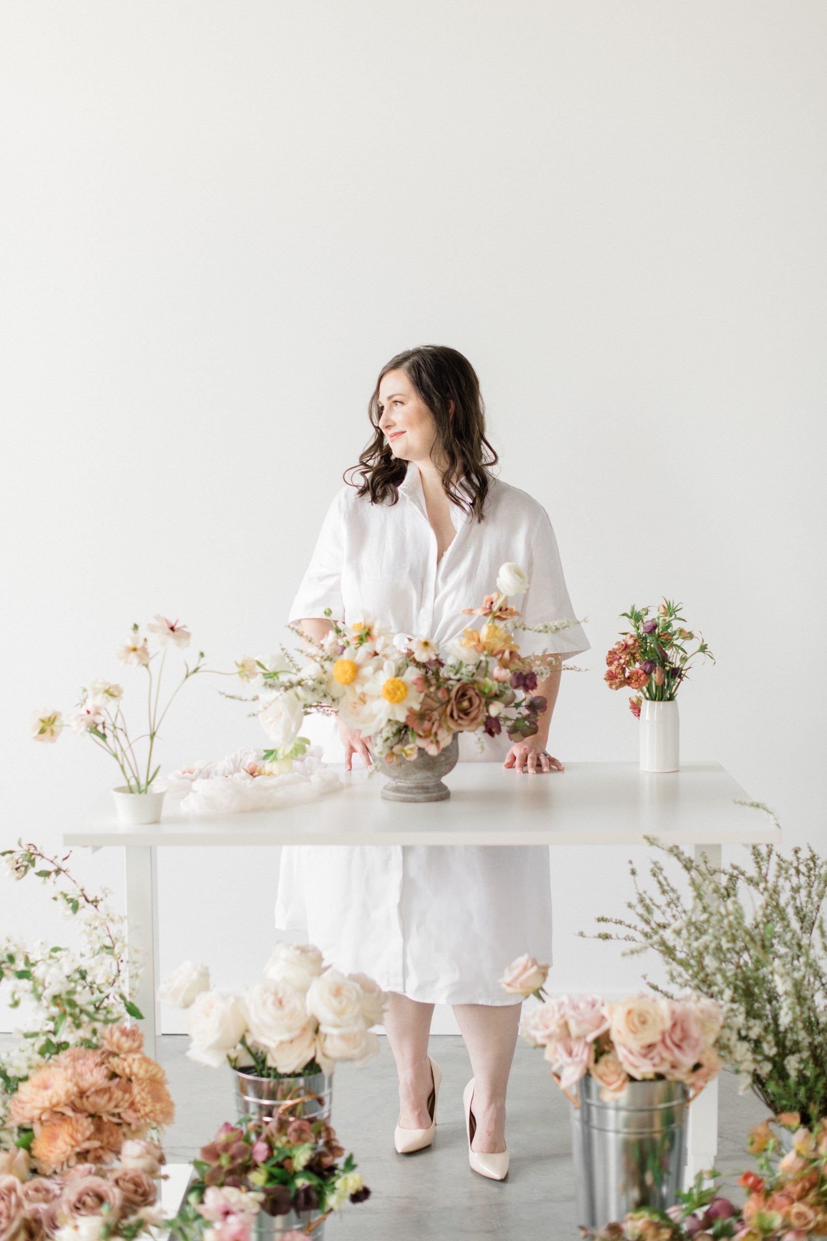 Owner Carolyn Kulb standing in a flower studio, surrounded by flowers