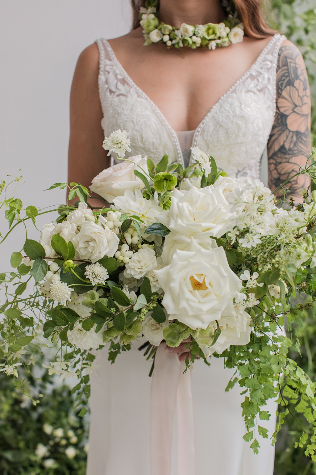 a white wedding bouquet being held by a bride, containing scabiosa