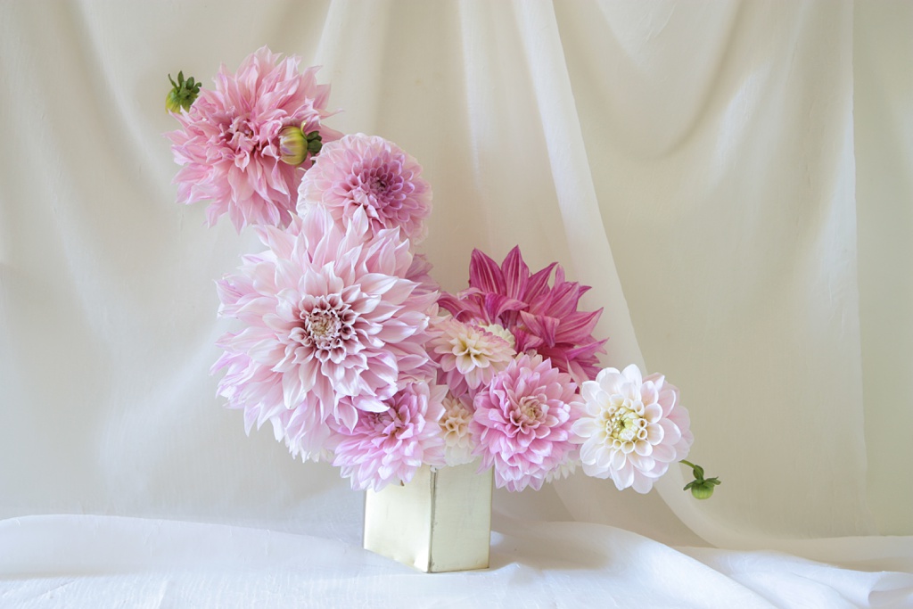 an asymmetrical vase of pink dahlias