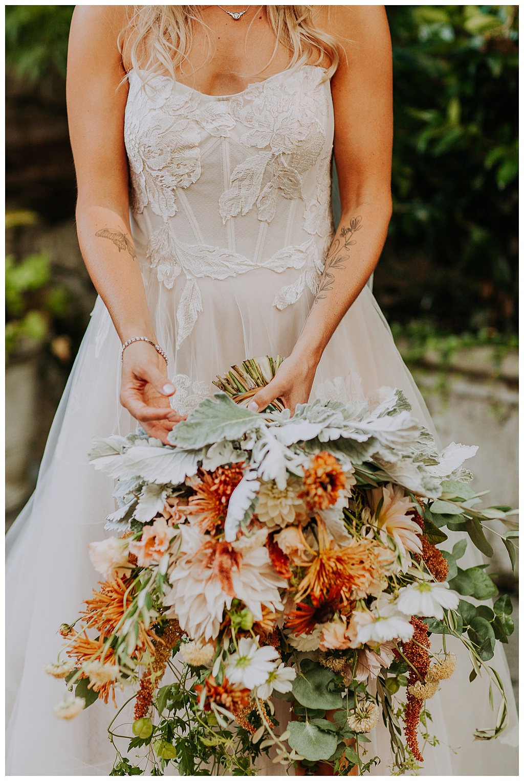 The bride holds the bouquet full of fall wedding flowers
