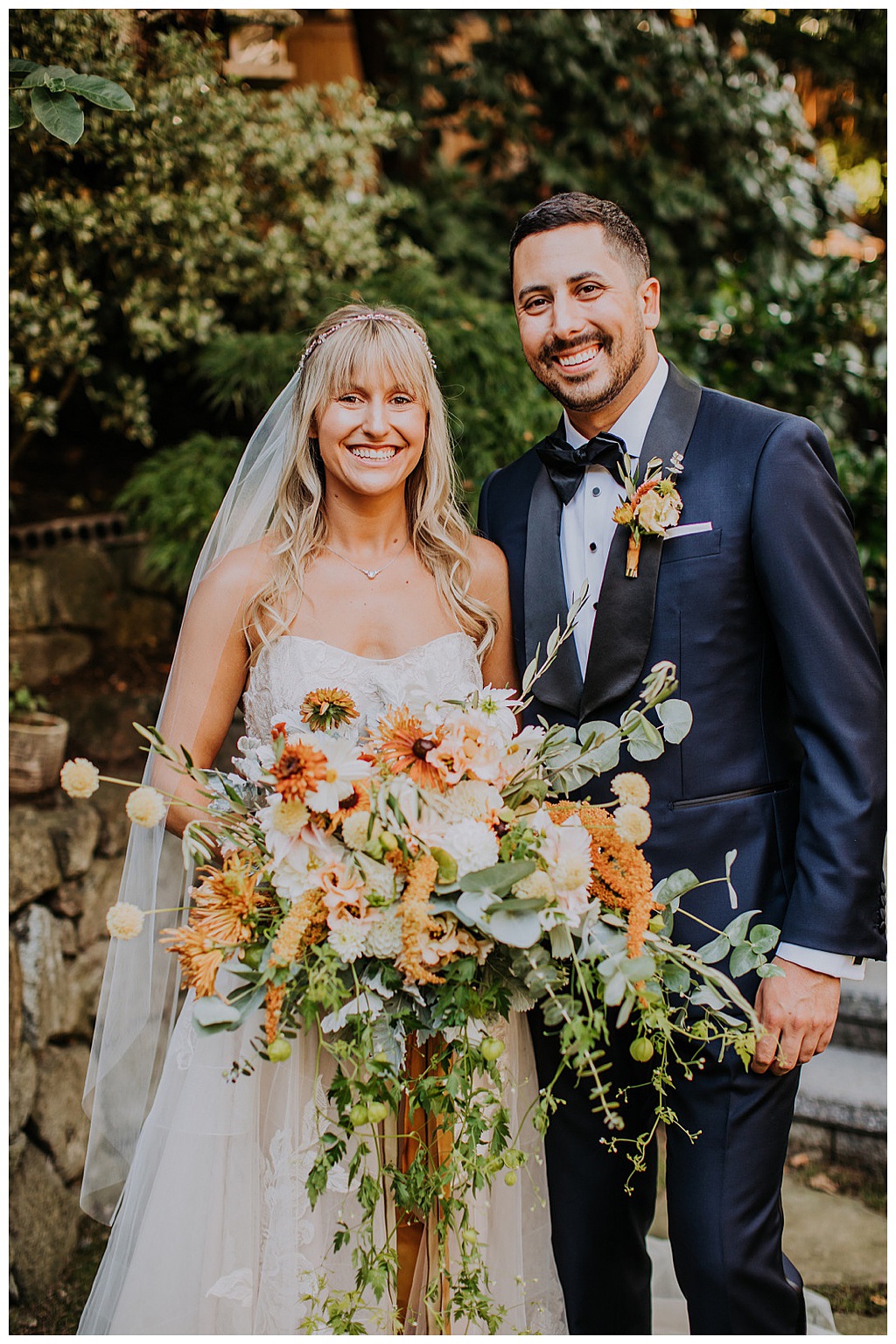 The couple smiling and holding the cascading bouquet