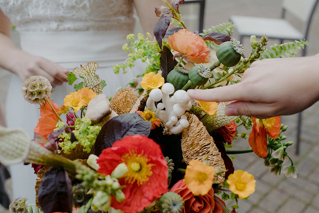 Someone touching the mushrooms in the bridal bouquet