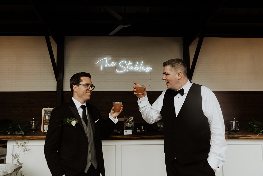 Two grooms toast with cocktails