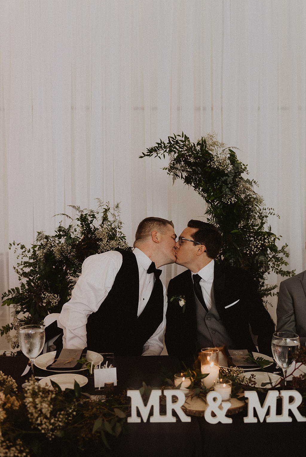 A gay couple kisses at their wedding head table