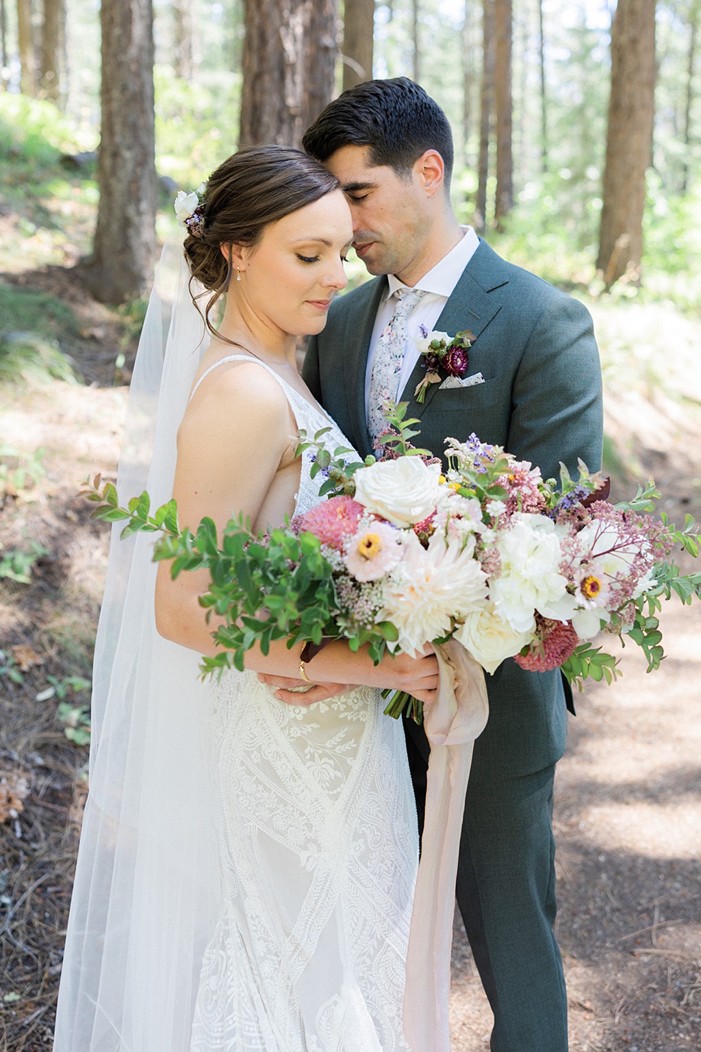 The bride and groom hold a bouquet in the forest for their Tierra Retreat Center wedding