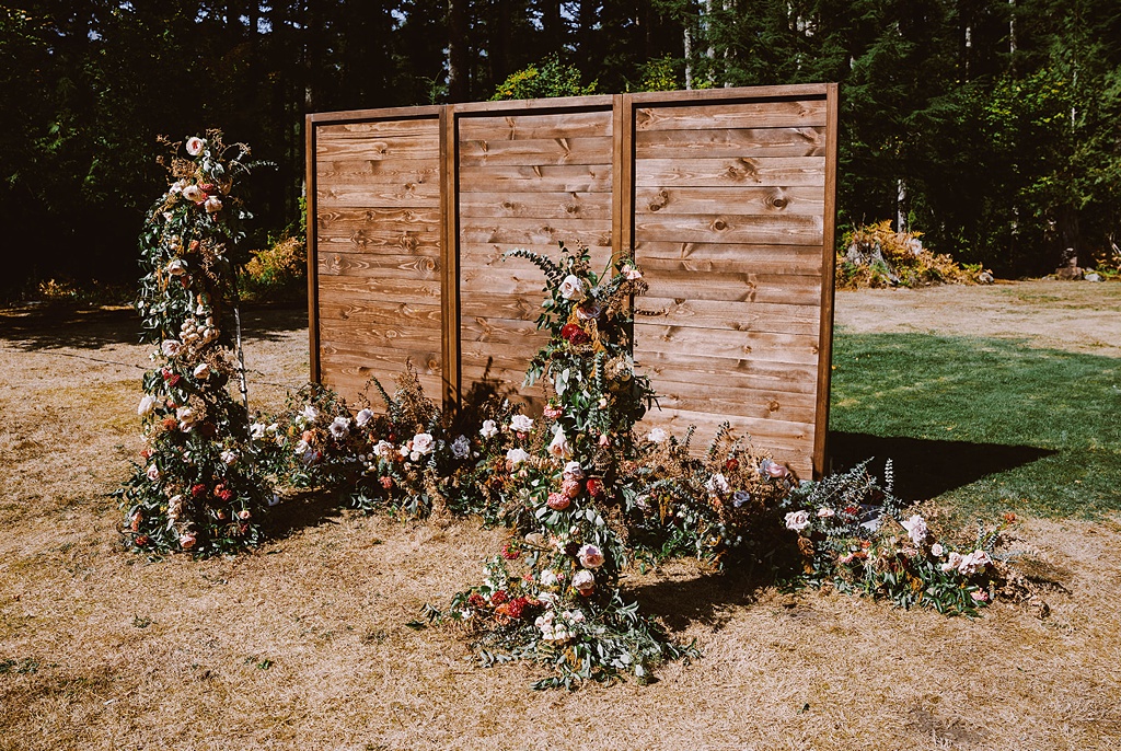 An asymmetrical wedding arch with floral backdrop for this summer wedding
