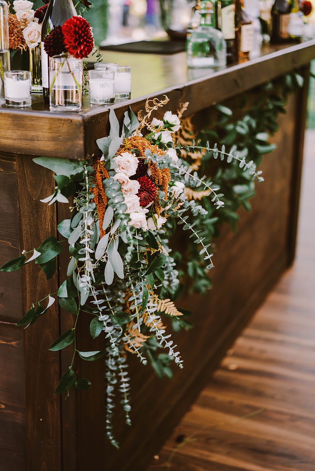 A bar floral installation full of textured greenery and blooms at this late summer wedding