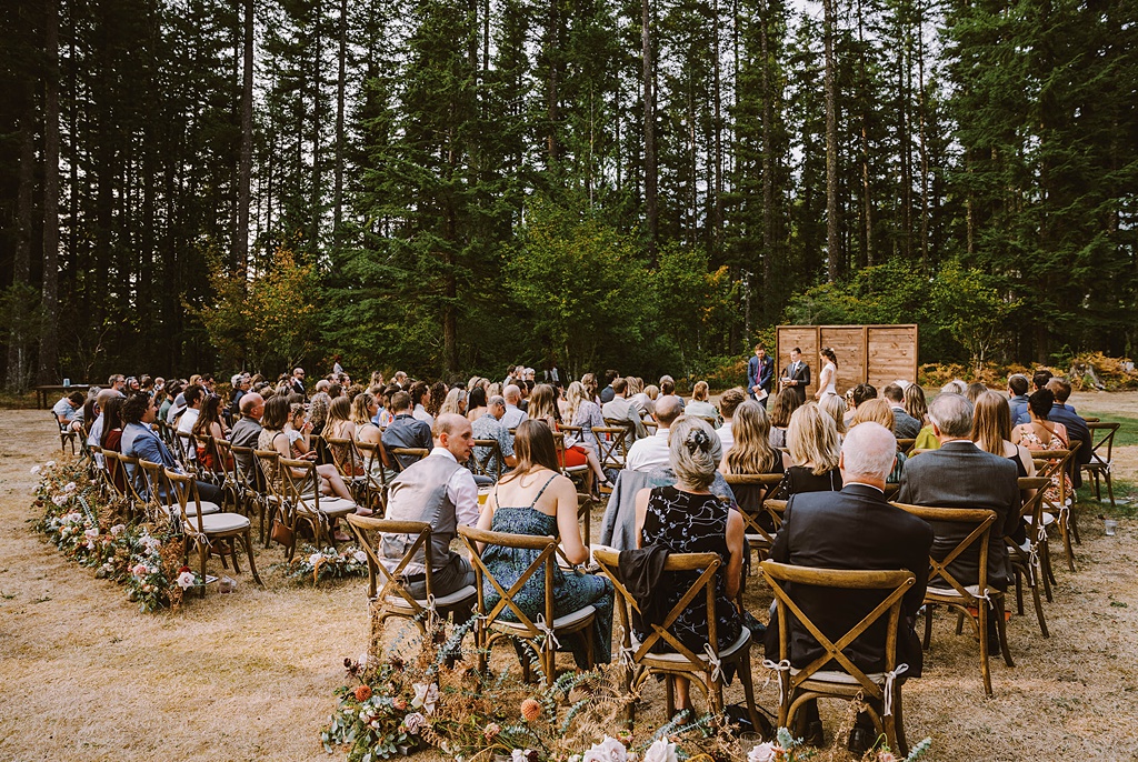 The wedding ceremony, including florals at the back of the aisles, at this summer wedding