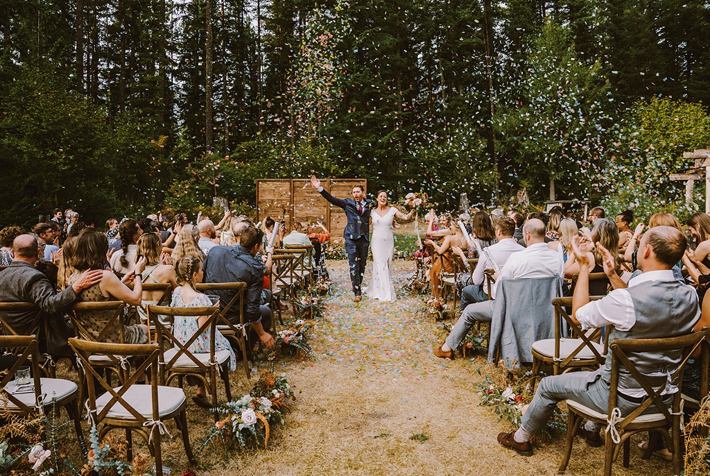 The couple walk down the aisle, just married, at this summer wedding