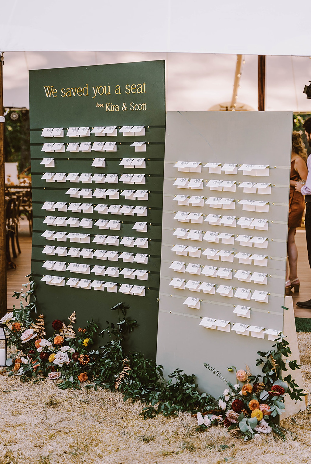 A wedding seating chart with escort cards and a floral installation